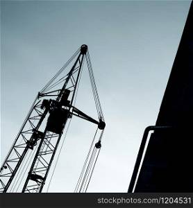 Silhouette of a building crane and details of an unfinished building. Lifting machine silhouette.