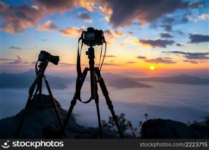 Silhouette of a camera on tripod at sunrise.