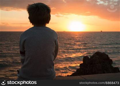 Silhouette of a Child in Front of Sea at Sunset