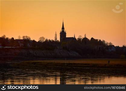 silhouette of a church in the city of Cossebaude near Dresden on the river Elbe at sunset in the yellow red evening light. silhouette of a church in the city of Cossebaude near Dresden on the river Elbe at sunset in the evening light