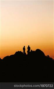Silhouette of a couple of men over a colorful sunset during a sunny day