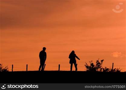 silhouette of a couple trekking in the mountian with a sunset