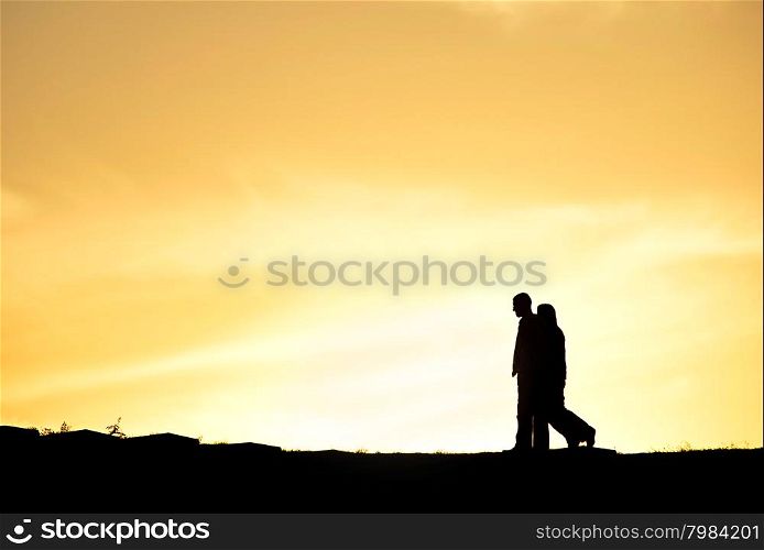 SIlhouette of a couple walking at sunset on a hill