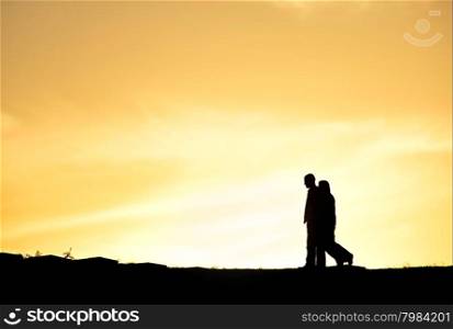 SIlhouette of a couple walking at sunset on a hill