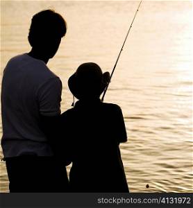 Silhouette of a father and his son fishing