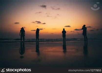 Silhouette of a group of friends Seaside during sunset
