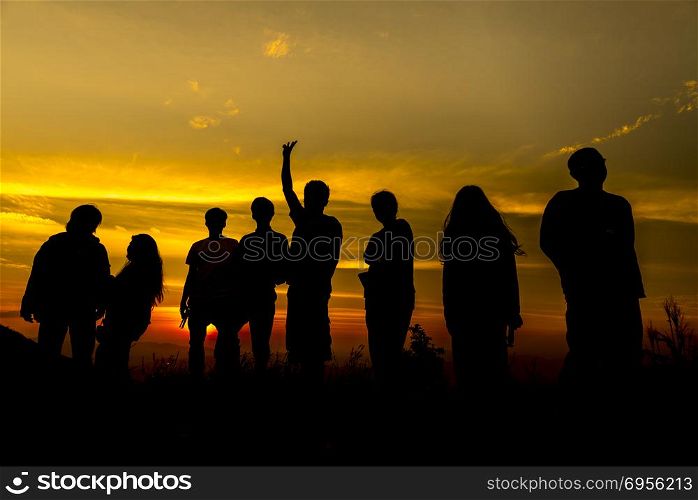 Silhouette of a group of people at sunset .