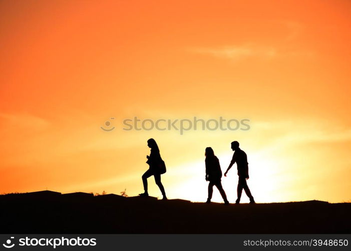 SIlhouette of a group of people walking at sunset on a hill