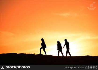 SIlhouette of a group of people walking at sunset on a hill