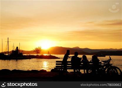 Silhouette of a happy family enjoy beautiful sunset view in English Bay, Vancouver BC Canada