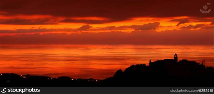 Silhouette of a little coastal town, church on the hill on sunset light, amazing panoramic view, stunning cityscape