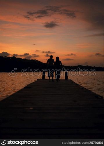Silhouette of a man and a woman standing on a pier