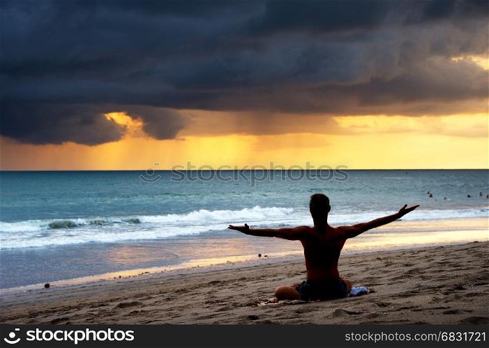 Silhouette of a man doing yoga exercise on the beach. Bali island, Indonesia