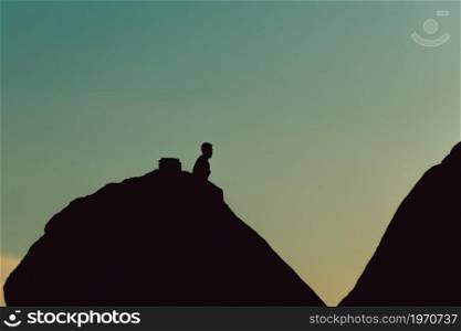 Silhouette of a man over a mountain during a blue hour sunset with copy space, liberty and reflection concepts