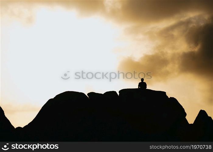 Silhouette of a man over a mountain during a blue hour sunset with copy space, liberty and reflection concepts