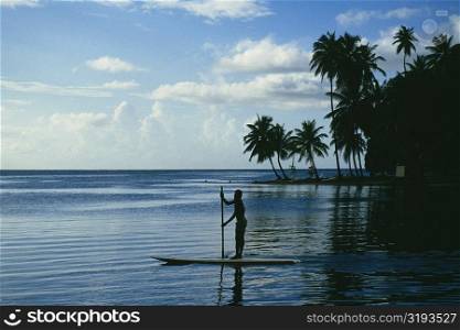 Silhouette of a man rowing a boat in a calm sea, St. Lucia
