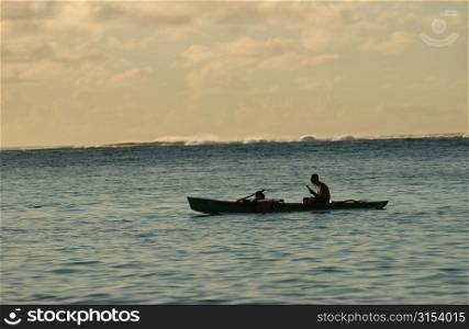 Silhouette of a man rowing a boat in the sea, Moorea, Tahiti, French Polynesia, South Pacific