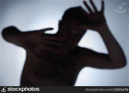 Silhouette of a man shielding his face with his arms