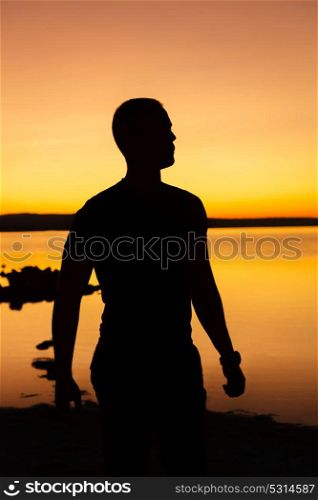 Silhouette of a man standing in the beach at sunset