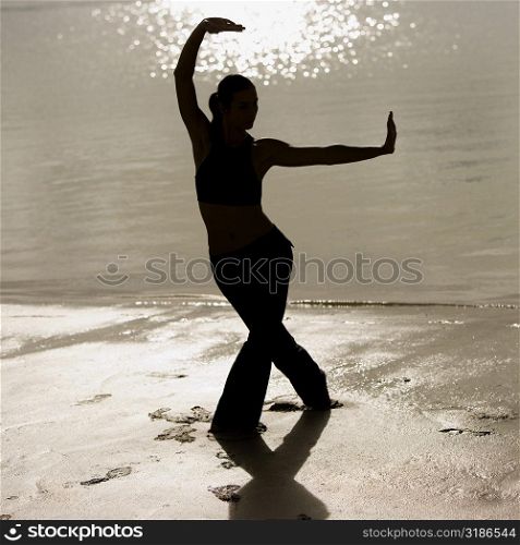 Silhouette of a mid adult woman exercising on the beach