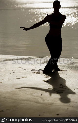 Silhouette of a mid adult woman exercising on the beach