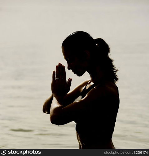 Silhouette of a mid adult woman meditating in water