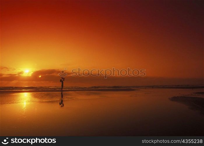 Silhouette of a person carrying a baby on the beach