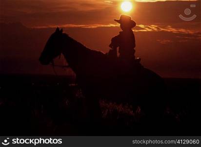 Silhouette of a person riding horseback at sunset