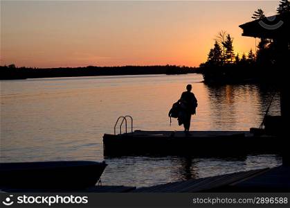 Silhouette of a person walking on a boardwalk, Lake of the Woods, Ontario, Canada