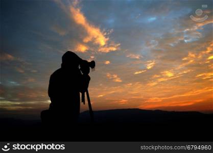 silhouette of a photographer taking pictures of the beautiful sunrise