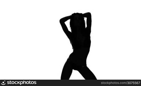 Silhouette of a sexy woman with long hair dancing with her hands raised isolated on white