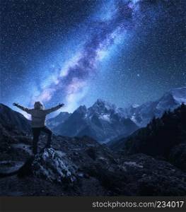 Silhouette of a standing man with raised up arms on the stone, mountains and starry sky with Milky Way at night in Nepal. Bright stars. Travel. landscape with mountain ridge and galaxy. Space