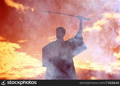 Silhouette of a warrior with a sword in the smoke of a mountain war