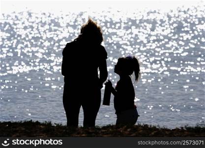 Silhouette of a woman and her daughter on the bank of a river