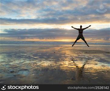 Silhouette of a woman jumping on a the beach at the sunset