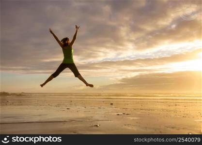 Silhouette of a woman jumping on a the beach at the sunset