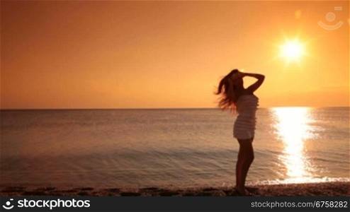 silhouette of a woman posing on the beach at sunset