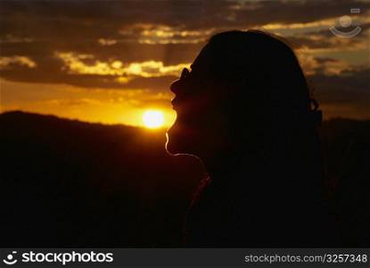 Silhouette of a woman pretending to eat sun at dusk