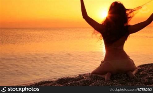 silhouette of a woman sitting on a beach at sunset