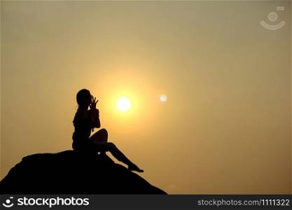 Silhouette of a woman sitting on a rock