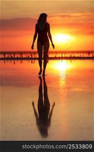 silhouette of a young slim woman in a swimsuit who dancing at sunset on the sea. summer holiday.. silhouette of a young slim woman in a swimsuit who dancing at sunset on the sea. summer holiday