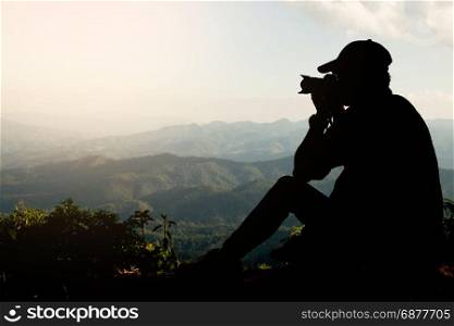 Silhouette of a young who like to travel and photographer, taking pictures of the beautiful moments during the sunset ,sunrise and mountain.
