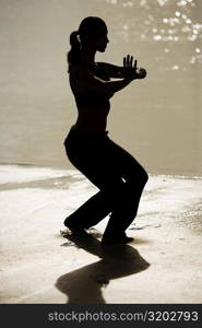 Silhouette of a young woman practicing martial arts on the beach