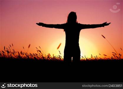 Silhouette of a young woman relaxing on a beautiful sunset of a summer day