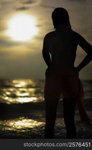 Silhouette of a young woman standing on the beach