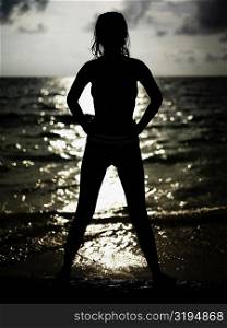 Silhouette of a young woman standing on the beach