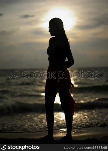 Silhouette of a young woman standing on the beach