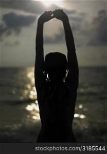 Silhouette of a young woman with her arms raised