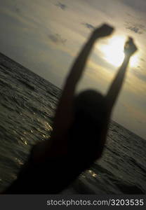 Silhouette of a young woman with her arms raised