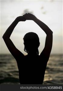 Silhouette of a young woman with her arms raised